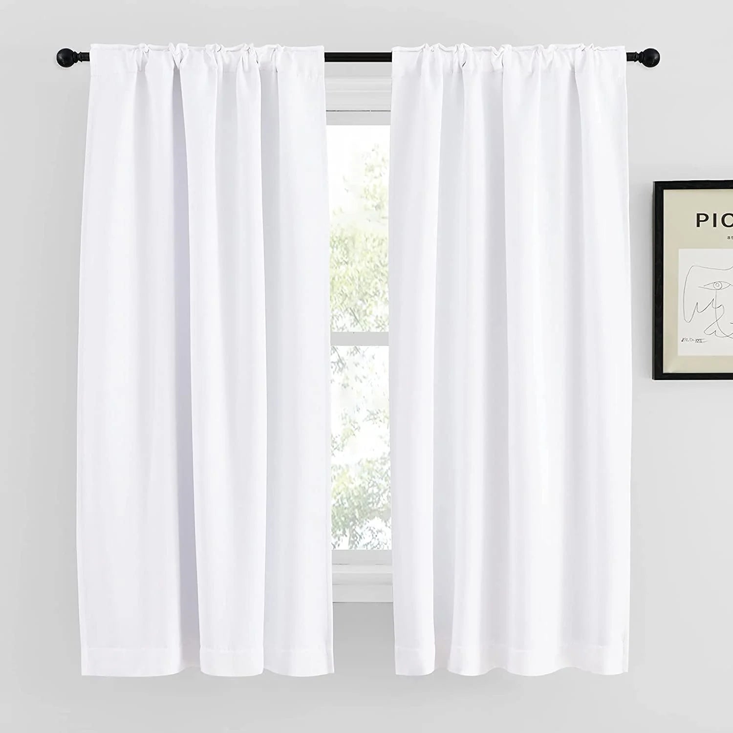 White rod pocket curtains hanging on a black curtain rod over a bright window