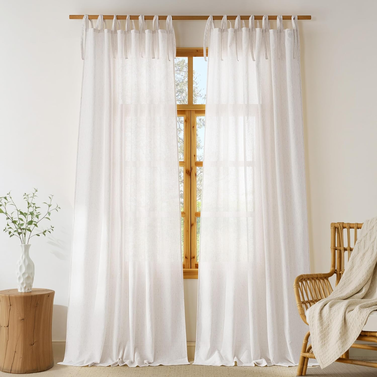 Two white semi-sheer linen tie-top curtains on a wooden rod, creating an airy feel.