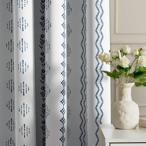 White curtains with varied vertical navy blue bohemian patterns, featuring floral, geometric, and dashed wavy designs.