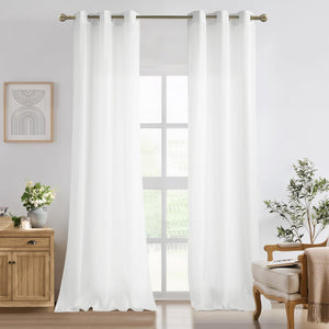 White opaque grommet top curtains hanging on a brass rod, covering a window in a bright living room.