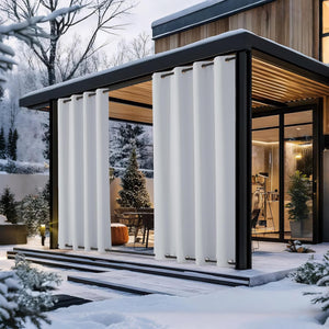 White grommet top outdoor curtains installed on a modern patio pergola in a snowy winter setting.