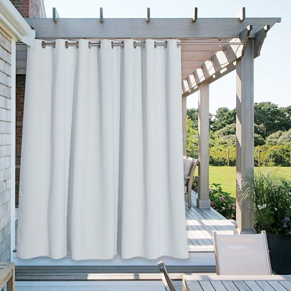 White outdoor curtain with silver grommets hangs from a wooden pergola, providing privacy on a sunny patio deck.