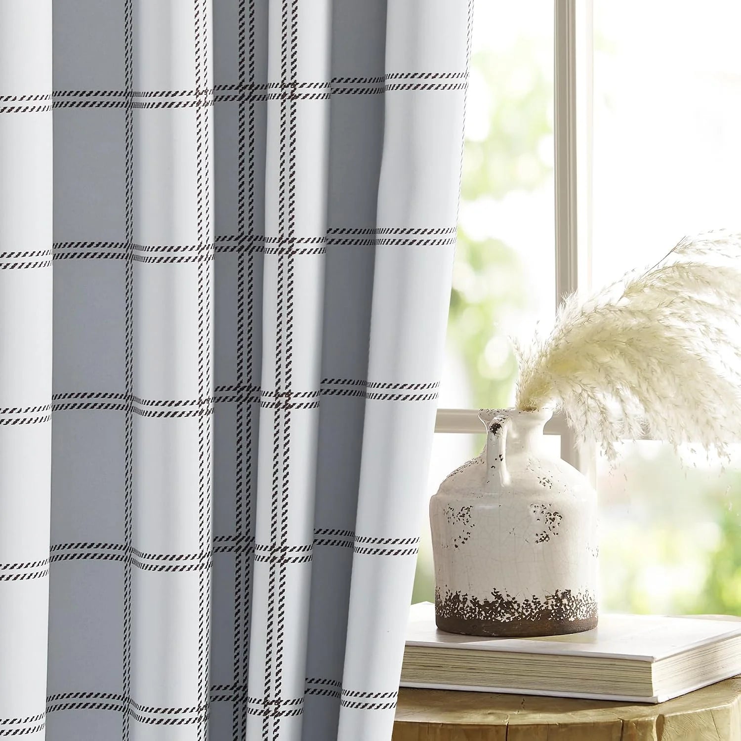 White plaid curtain panel beside a bright window with a rustic ceramic vase