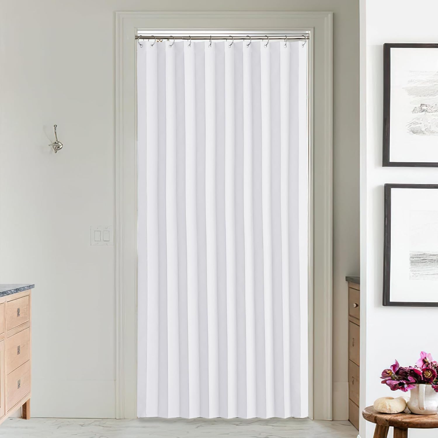 White pleated fabric doorway curtain hung on a silver rod in a modern bathroom setting.