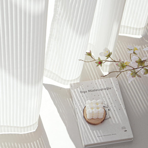White pleated sheer curtain allowing soft sunlight to diffuse, creating gentle shadows.
