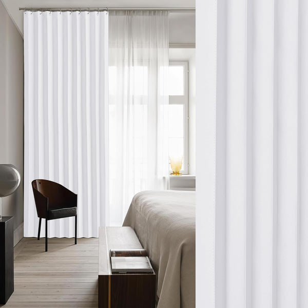 White pleated track curtains creating a modern room divider in a bright, minimalist bedroom setting.