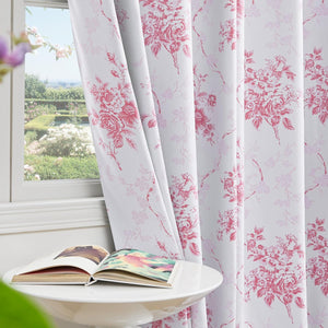 White window curtains featuring a detailed red floral toile pattern, overlooking a sunny garden.