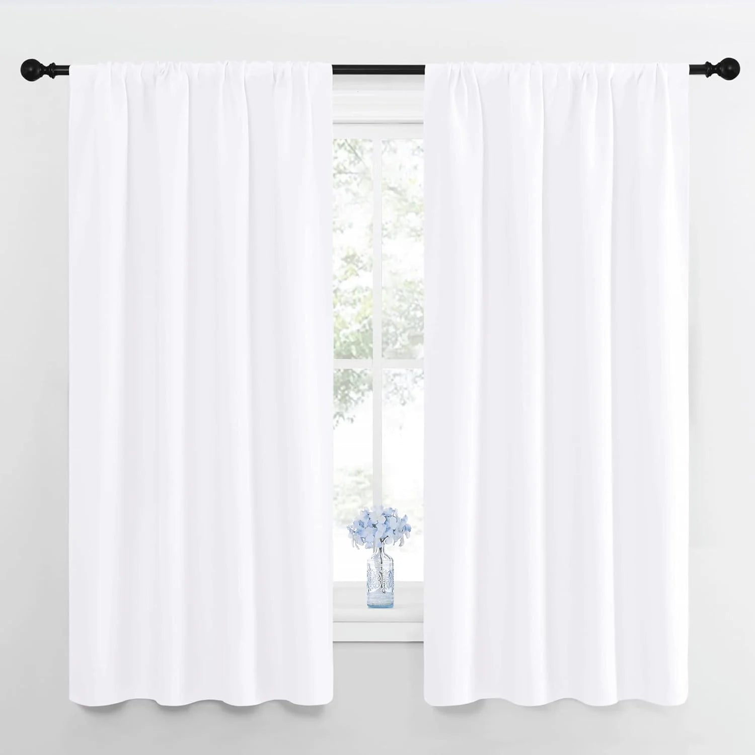 Clean white rod pocket curtains on a black rod framing a bright window.