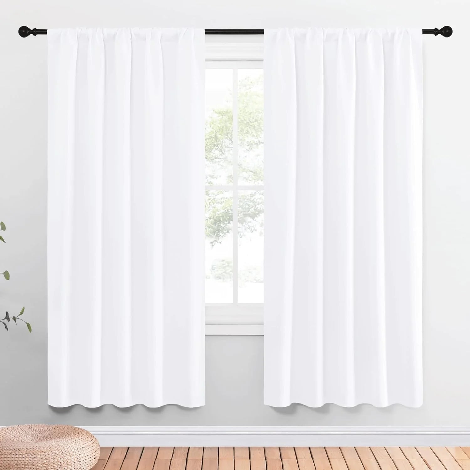 White rod pocket curtains on a black rod in a bright, minimalist room with wood floor.