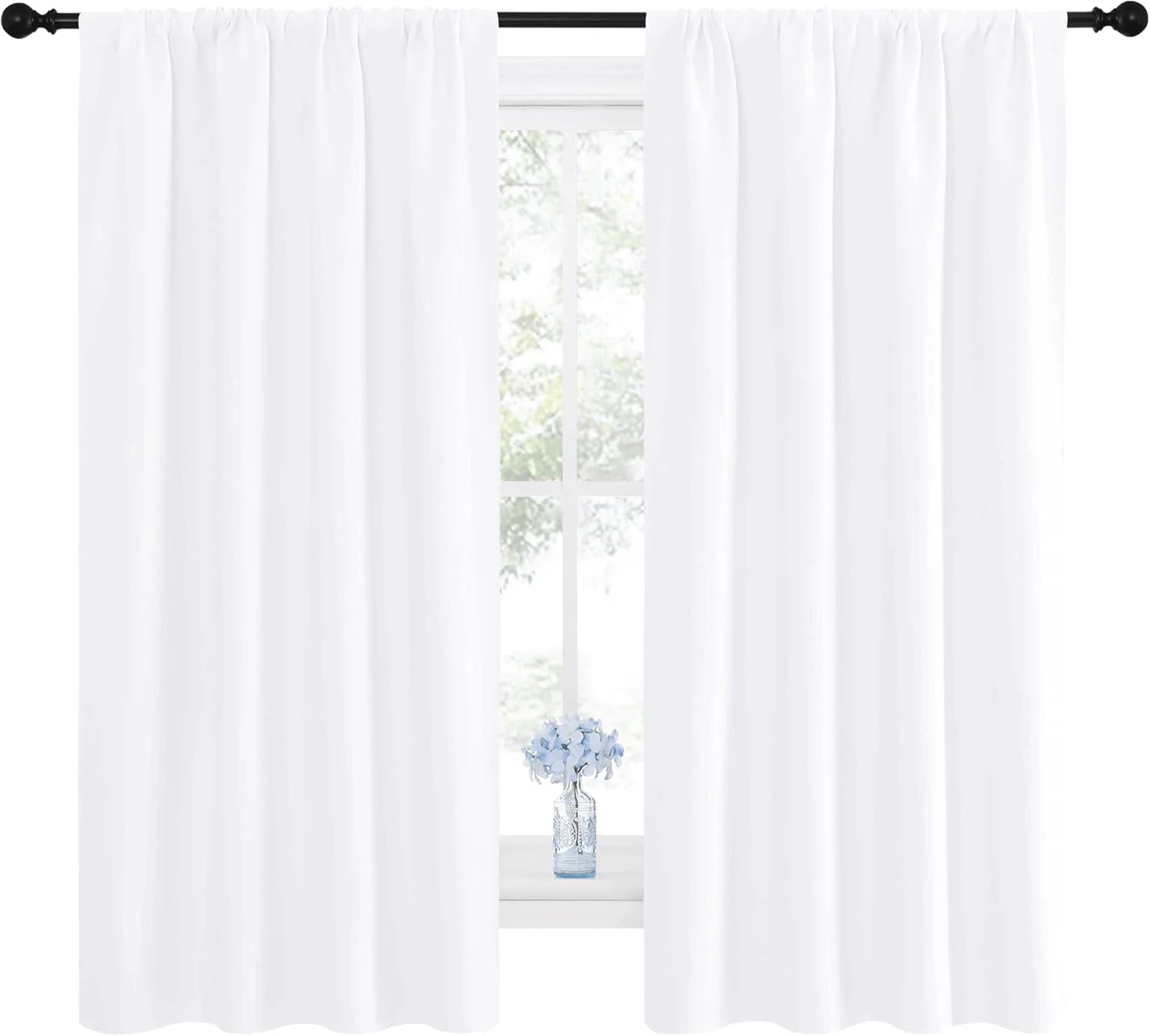 Bright white rod-pocket curtains on black rod over window with small blue flower vase.
