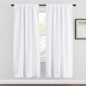 Pair of white rod pocket curtains on a black rod, filtering light from a window in a modern room.
