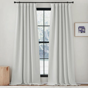 Pair of white opaque rod pocket curtains hang on a black rod, puddled on the floor.