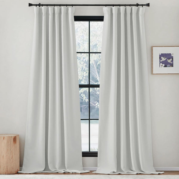 Pair of white opaque rod pocket curtains hang on a black rod, puddled on the floor.