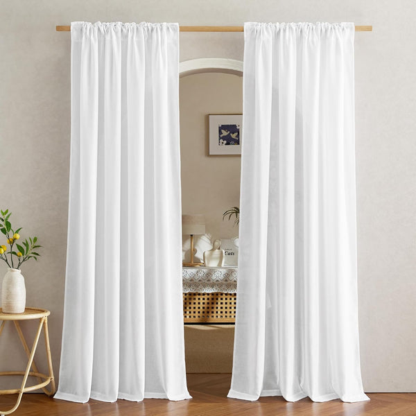 Two panels of white rod pocket voile curtains hanging on a wooden rod, framing an arched doorway.