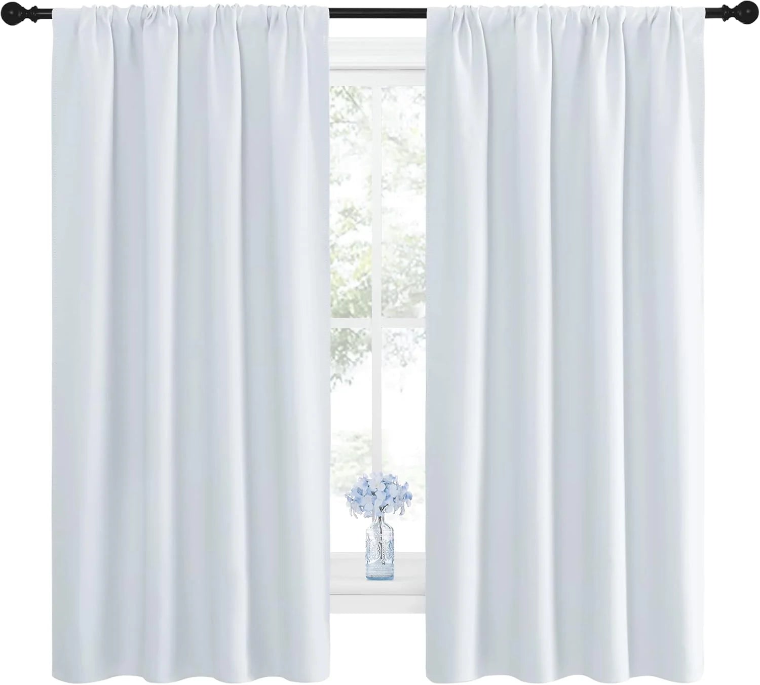 White rod pocket curtains hanging on a black curtain rod over a bright window