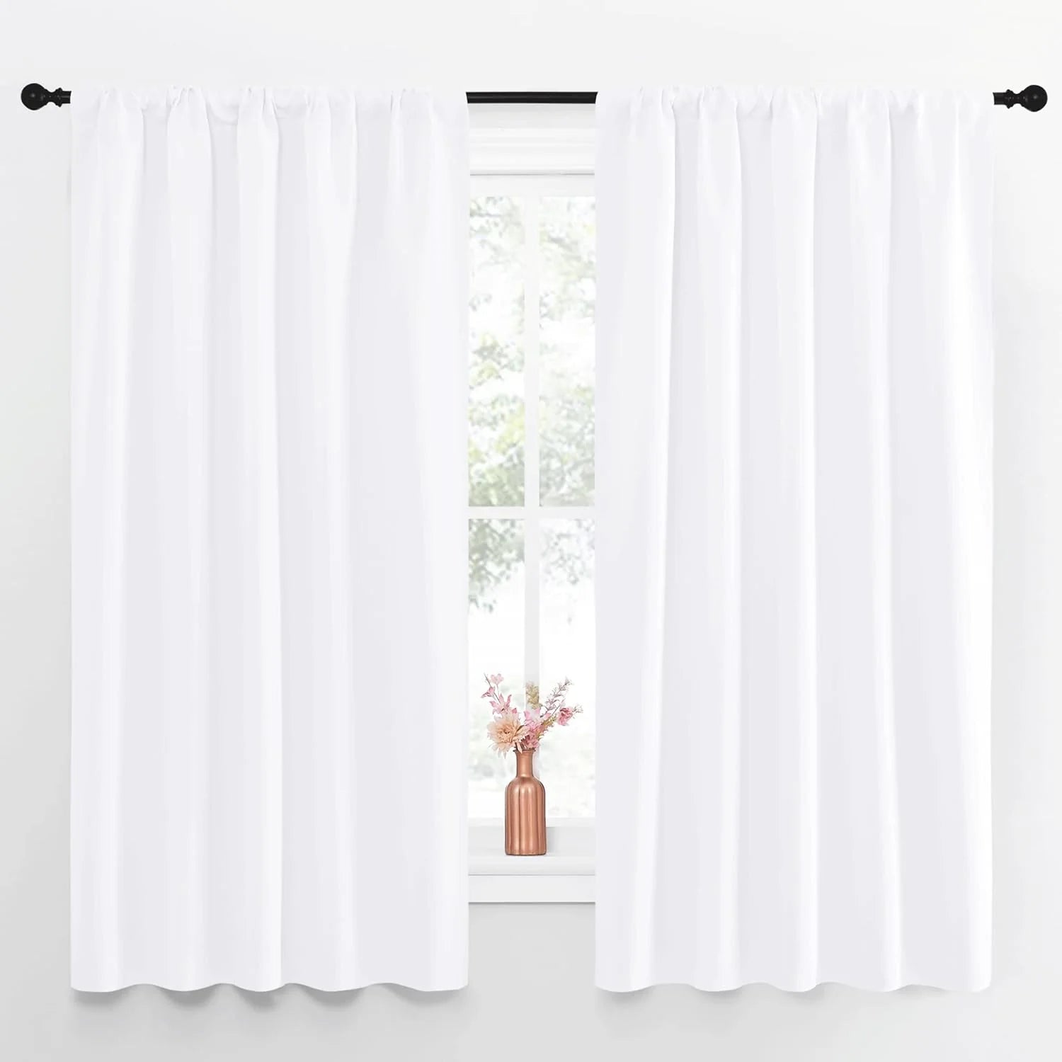 Pair of white rod pocket curtains on a black rod, framing a bright window.