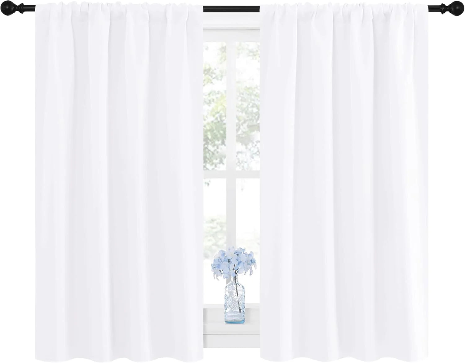 Pair of bright white rod pocket curtains on a black decorative rod, with blue flowers on windowsill.