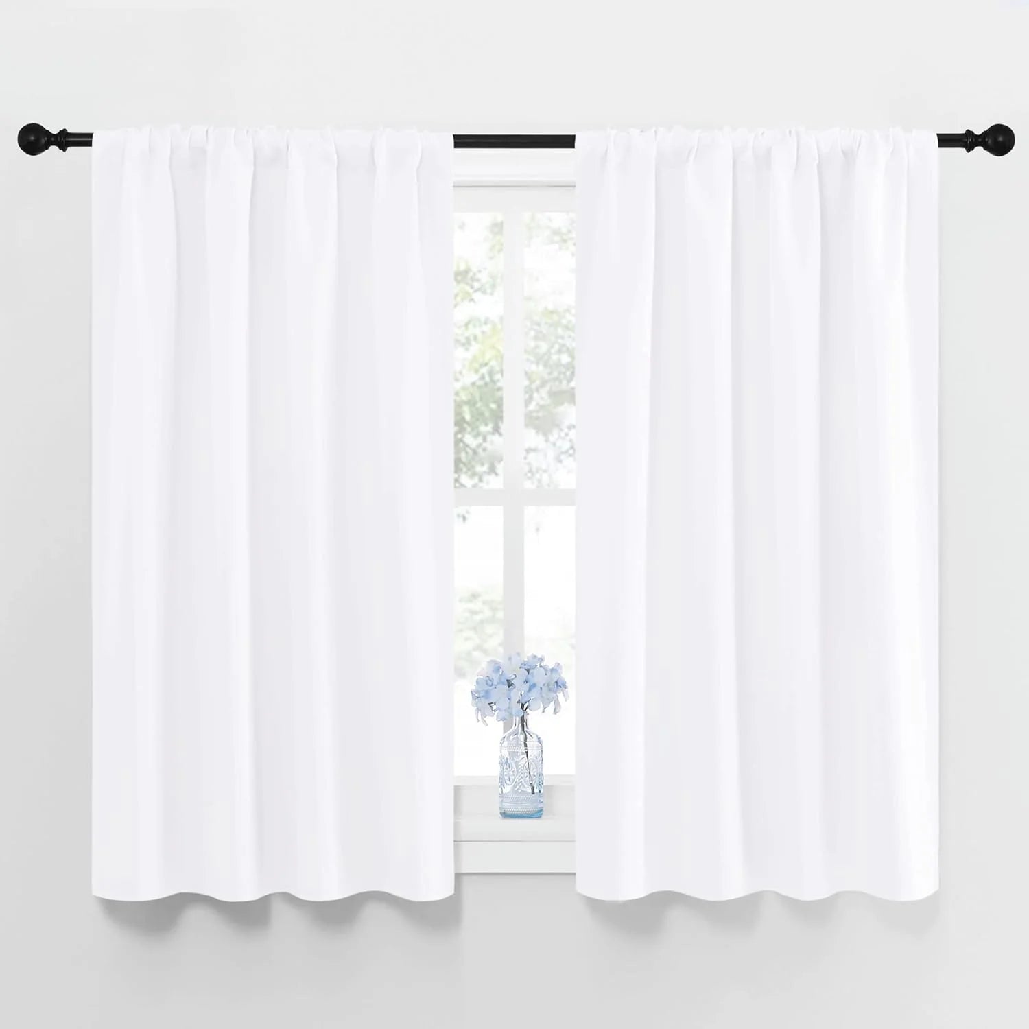 Pair of white rod pocket curtains on black rod, blue flowers on windowsill.