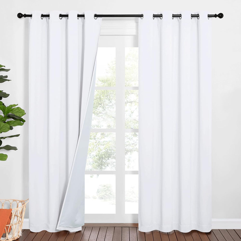 Bright white room darkening curtains with black grommet tops hanging on a window rod, one panel slightly open.