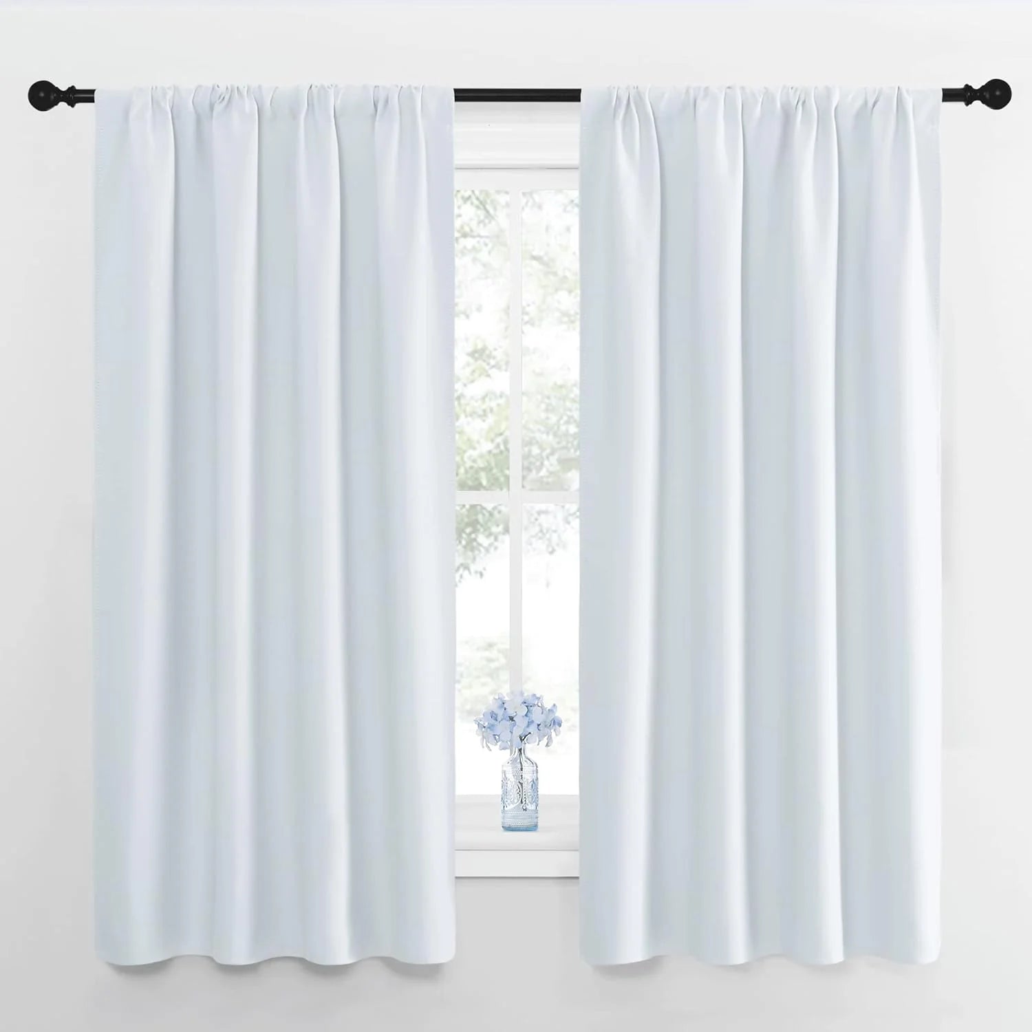 White room darkening curtains with rod pocket tops on a black rod, overlooking a bright window.