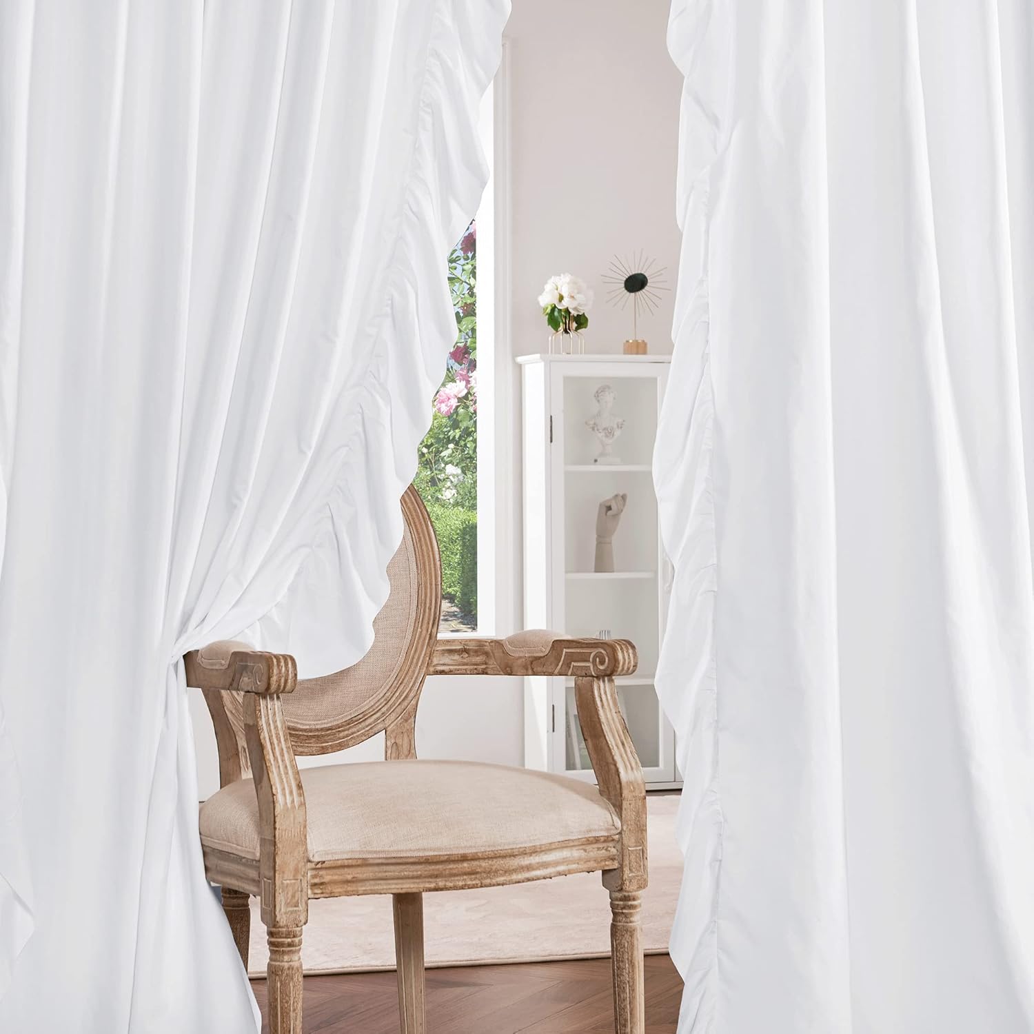 Elegant white ruffled edge window curtains gracefully frame a room with a vintage armchair.