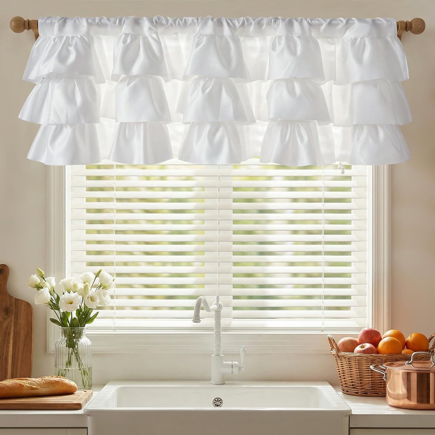 White tiered ruffle valance hanging on a wooden rod above a bright kitchen window with a sink.