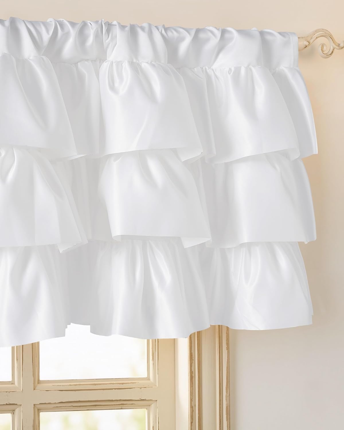 White ruffled tiered window valance made from smooth fabric, styled over a light-colored window frame.