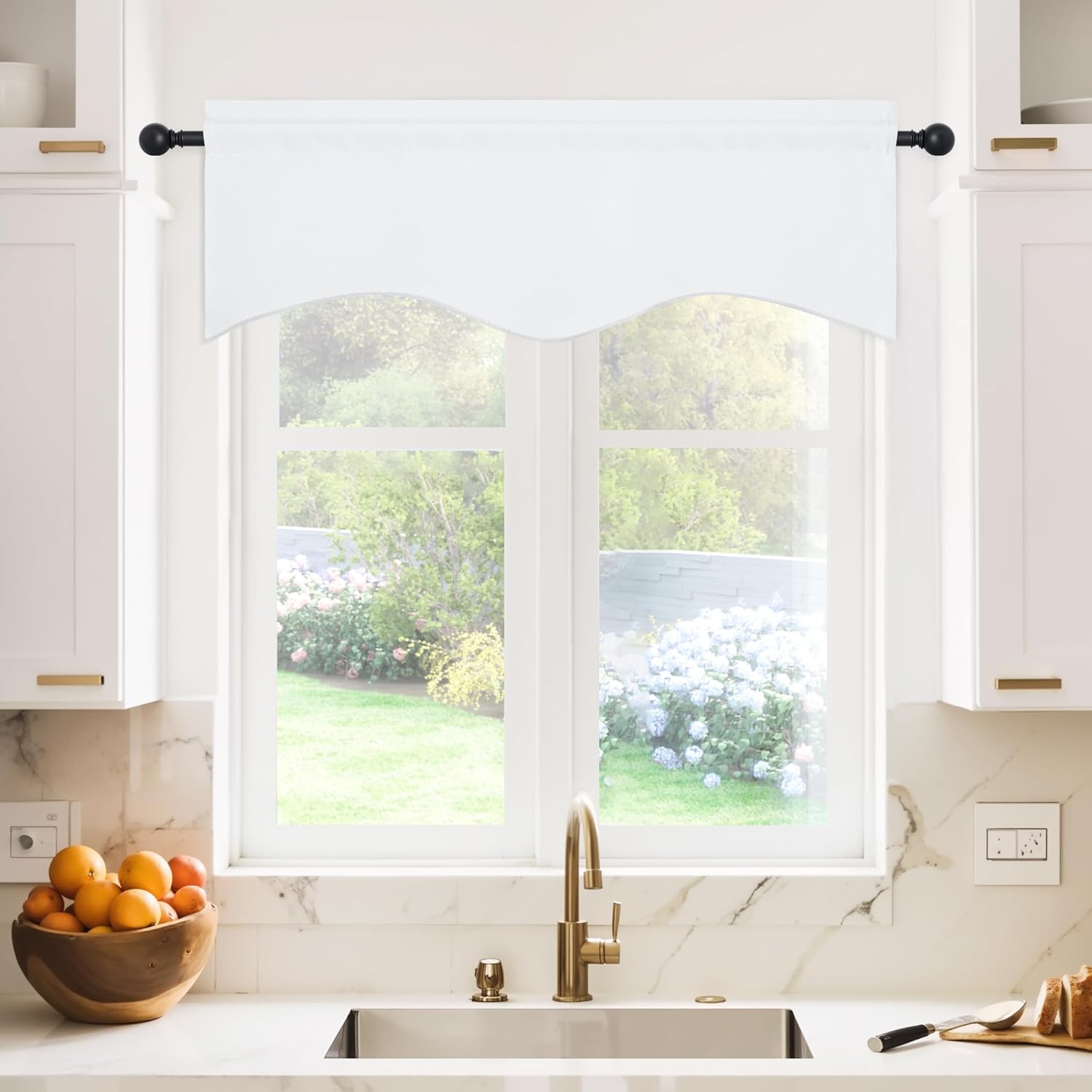 White scalloped rod pocket valance on a black rod, above kitchen window with garden view.