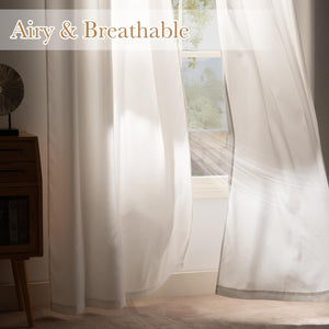 Light filtering white sheer curtains hanging in a window, sunlight creating an airy glow.