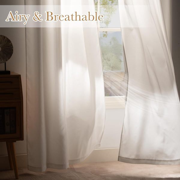 Light filtering white sheer curtains hanging in a window, sunlight creating an airy glow.