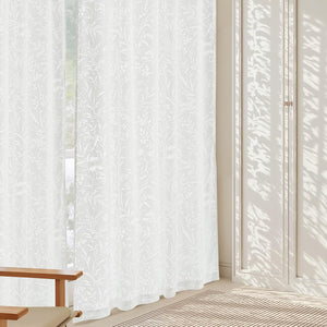 Pair of white sheer curtains with delicate botanical leaf and fern pattern, letting in soft daylight.