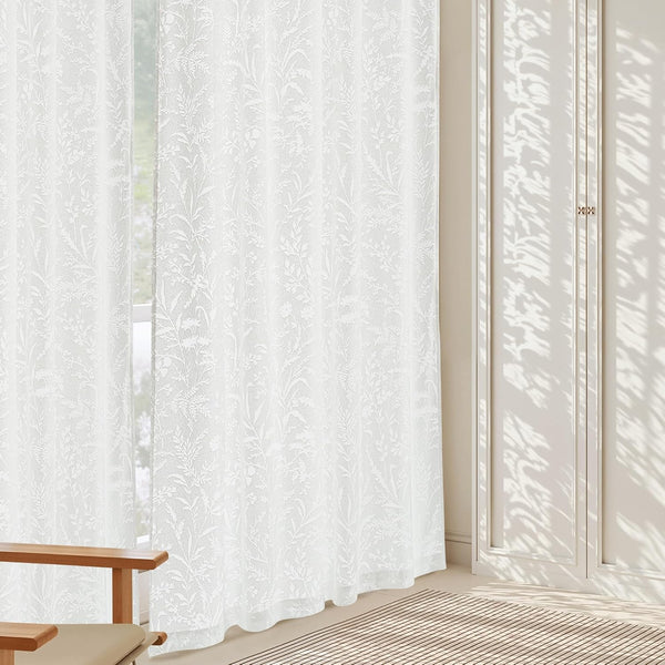 Pair of white sheer curtains with delicate botanical leaf and fern pattern, letting in soft daylight.