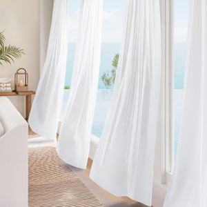White sheer flowing curtains in a light-filled room overlooking an ocean view with an infinity pool.
