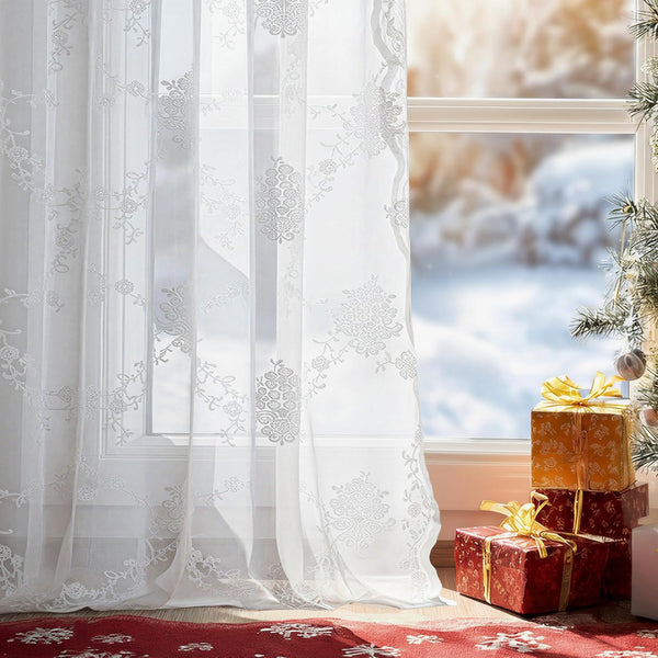 White sheer embroidered curtains featuring floral and snowflake patterns, filtering bright light.