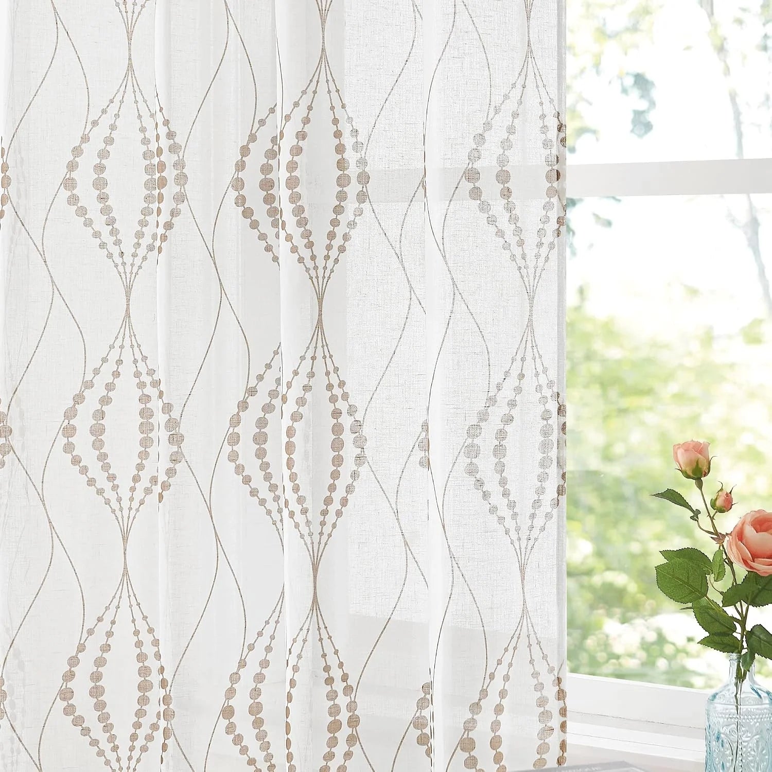 White sheer curtain with beige embroidered geometric pattern by a bright window