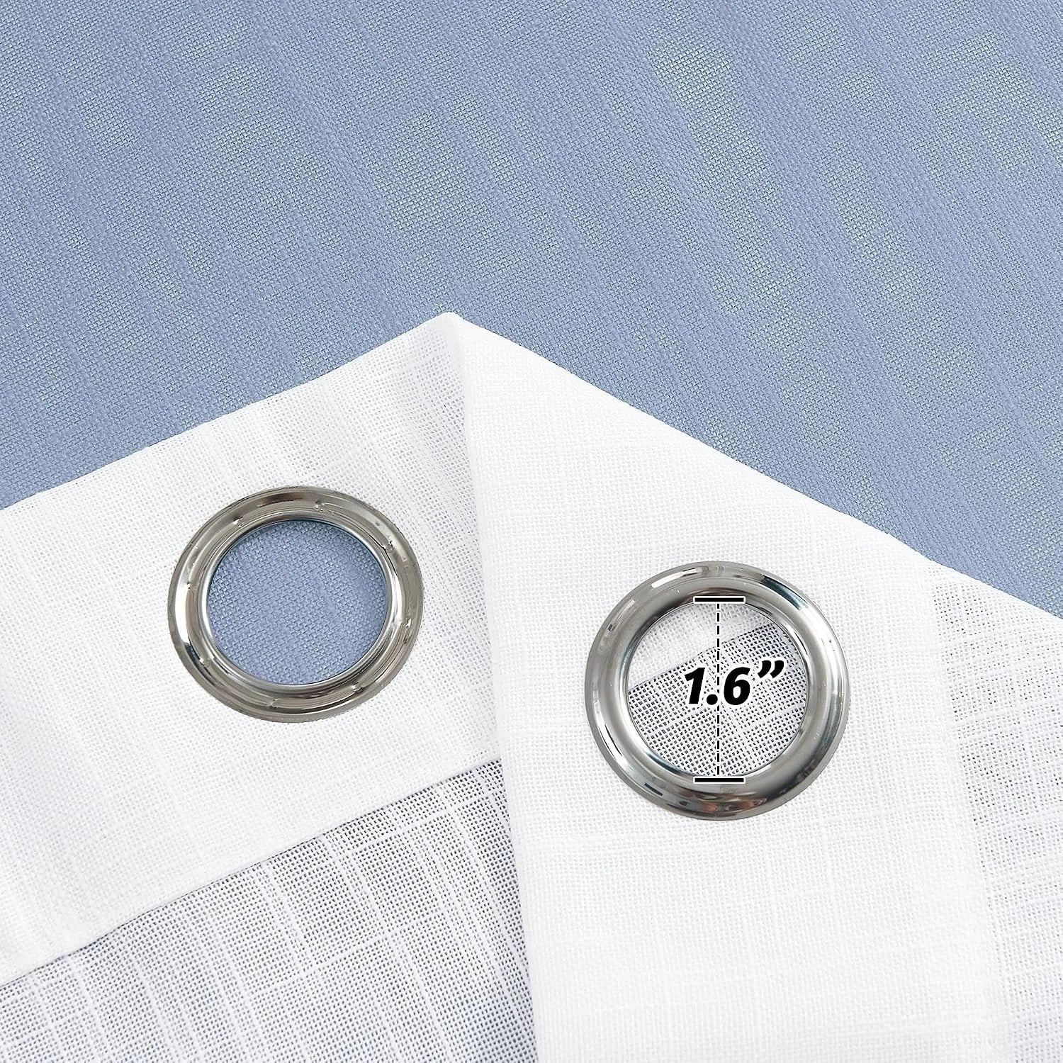 Close-up of white sheer curtain panels with silver grommets on blue fabric background
