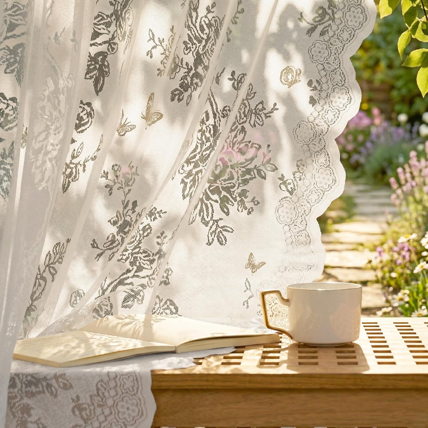 White sheer lace curtain with floral and butterfly design, scalloped edge. Bright sunlight reveals a garden.