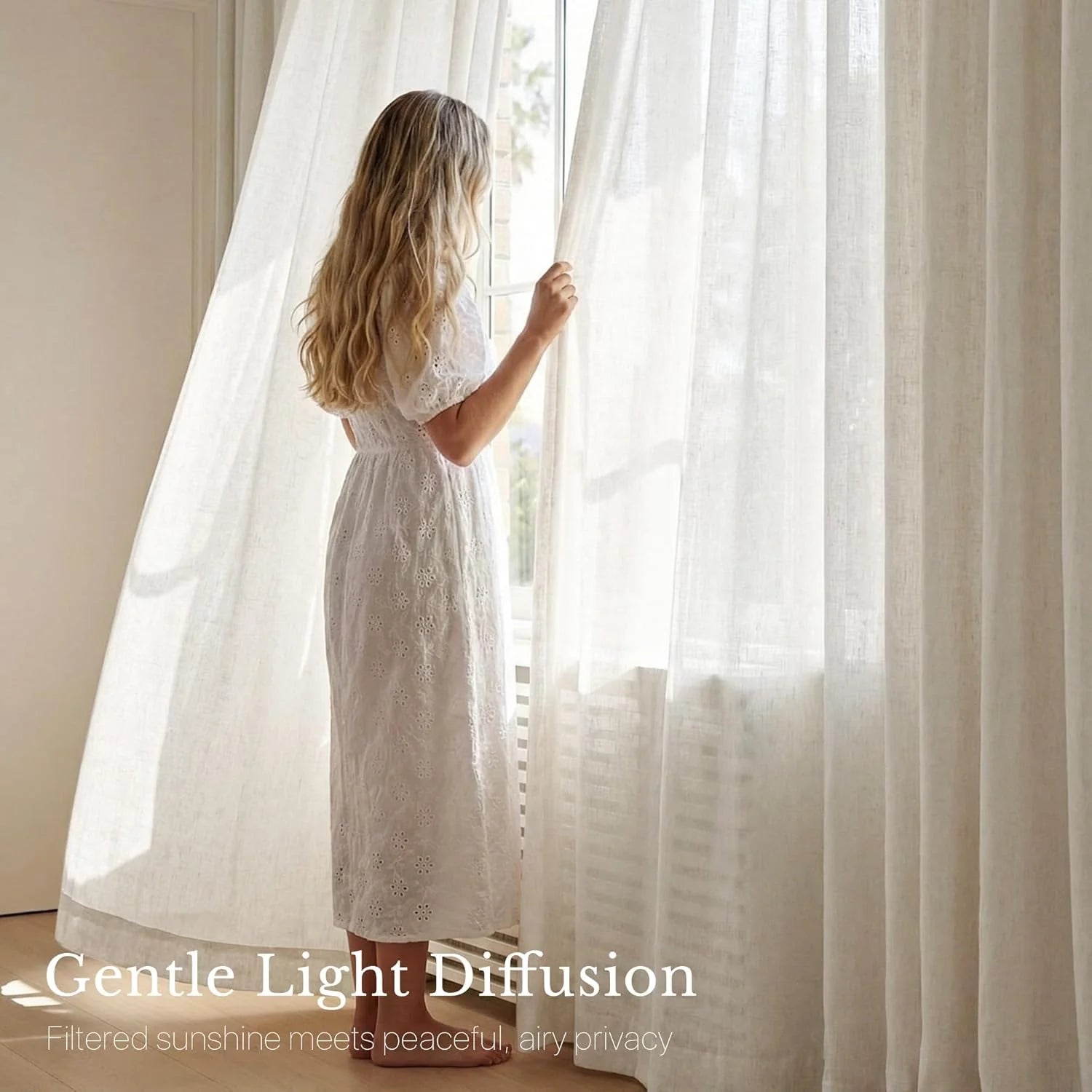 Long-haired woman in white eyelet dress at window, holding sheer white linen curtains that filter bright light.