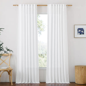 White sheer linen light-filtering curtains with rod pocket top hanging on a wooden rod in a bright room.