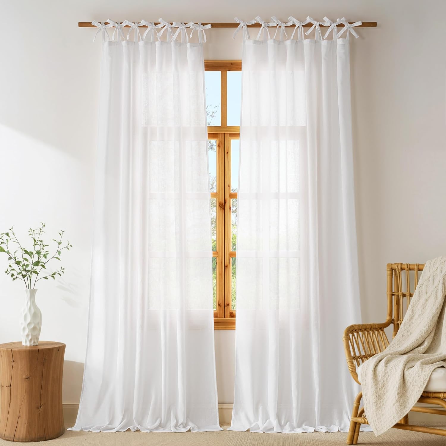 Two panels of white sheer linen tie-top curtains on a wooden rod, softly filtering light.