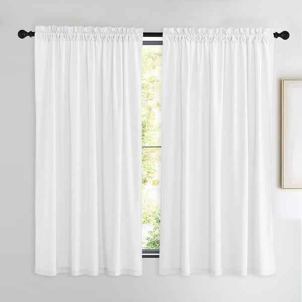 Pair of white sheer rod pocket curtains with gathered top, hung on a black rod. Green foliage outside.