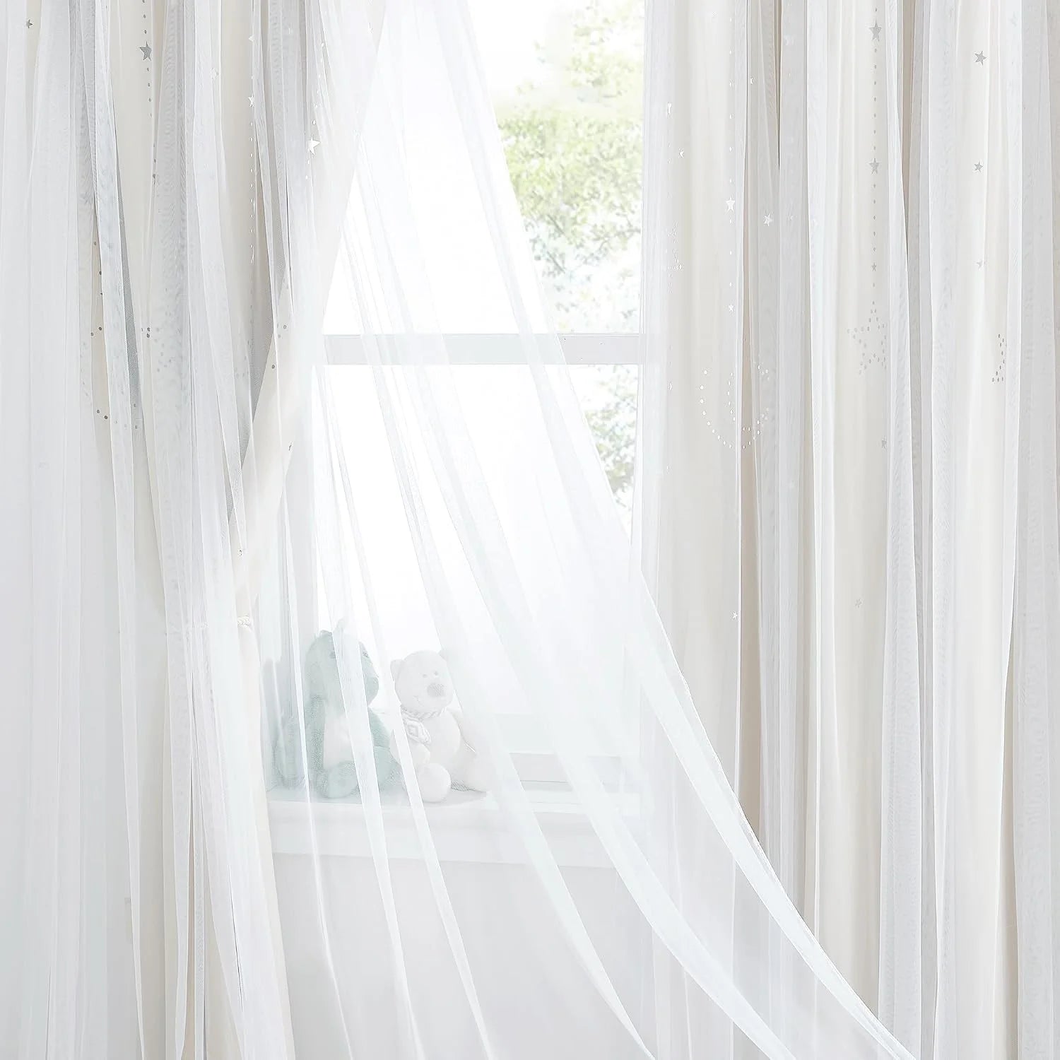 White sheer voile curtains with subtle star details hanging over a bright window
