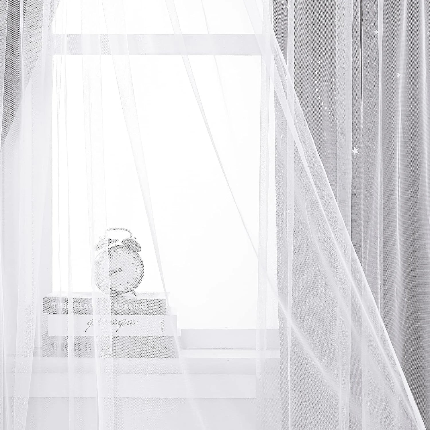 White sheer voile curtain draped over a bright window with books and a small alarm clock