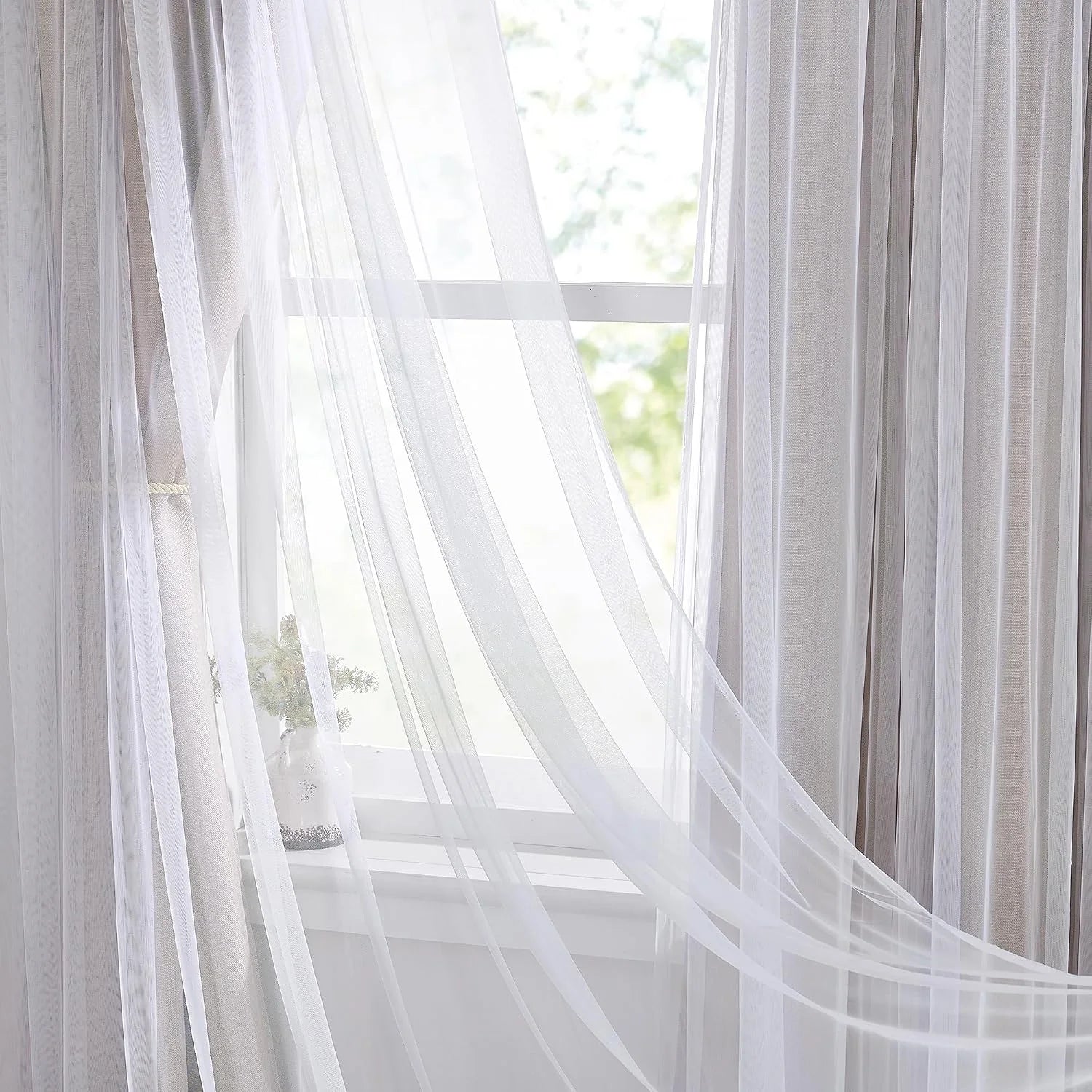 White sheer voile curtains draped over a bright window with soft natural light