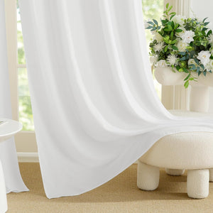 Bright white sheer curtain panel drapes softly by a window, filtering natural light into the room.