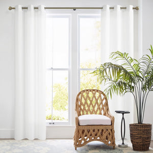 Bright white smooth curtains with metal grommets on a brass rod, framing a large window.