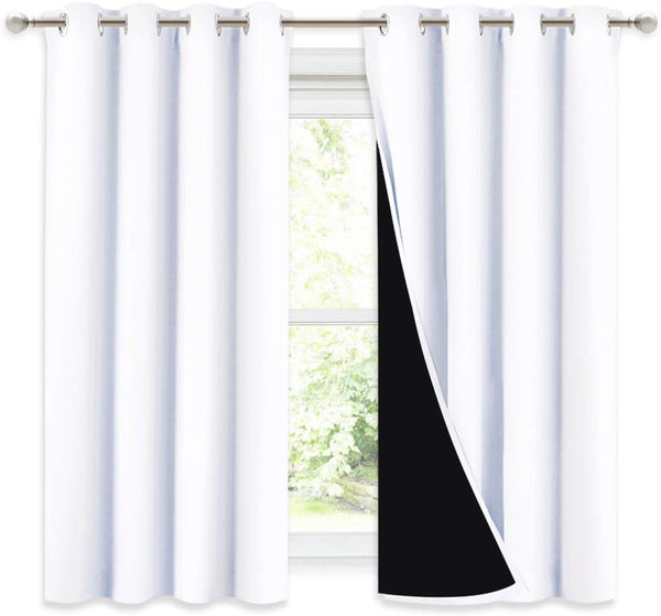 White solid blackout curtain panels with metal grommets hanging on a window rod, revealing black lining.