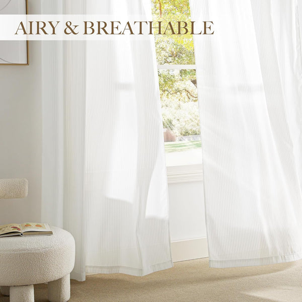 White sheer curtains with fine vertical stripes hanging in front of a window, allowing light to filter into the room.