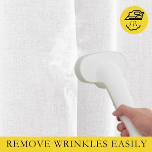 A hand uses a white handheld steamer to remove wrinkles from a white textured fabric curtain.
