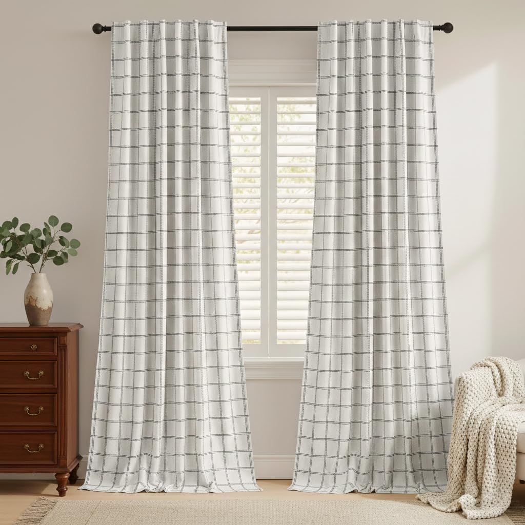 White textured curtains with dark grid plaid pattern, hanging from a rod over a window with shutters.